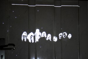 Auf eine Tür projizierte Schwarzweisszeichnung von Jenni Tietze. Portraits von Teilnehmern an einer Schweigeminute.