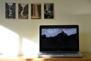 Ausstellungsansicht der Arbeit Bergfall von Sabine Höpfner. Monitor mit Videoarbeit vor Islandpostkarten von Wasserfällen.
