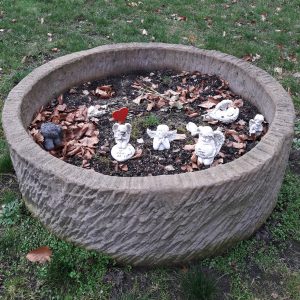 Ausgediente Engelsfiguren auf dem Friedhof Altona in einem Steinbehältnis, das an einen Brunnen gemahnt.