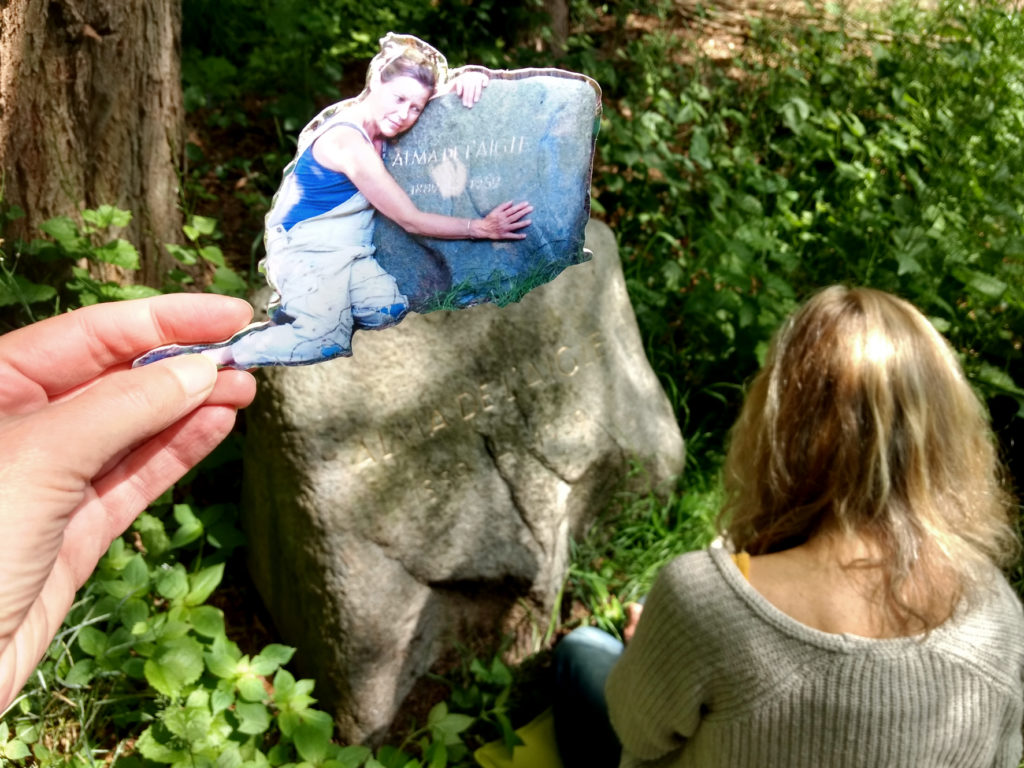 Die Hamburger Künstlerin Bettina Ulitzka-Allali vergoldet die Buchstaben auf Almas Gedenkstein im Mai 2020 und EVA hält ein Laubsägeobjekt mit einem Foto von Bettina ins Bild, wie sie nach der ersten Goldaktion den Stein umarmt.